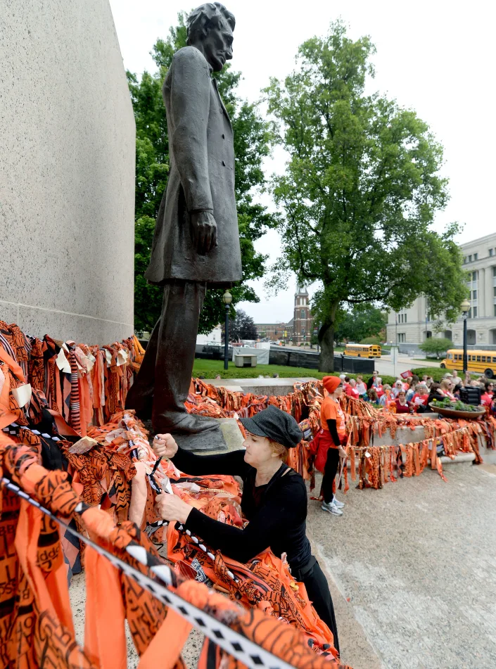 Artist Jacqueline Von Edelberg of Arts4Impact helps re-assemble the Highland Park Arts Memorial in front of the Lincoln statue at the state Capitol Tuesday, May 16, 2023.